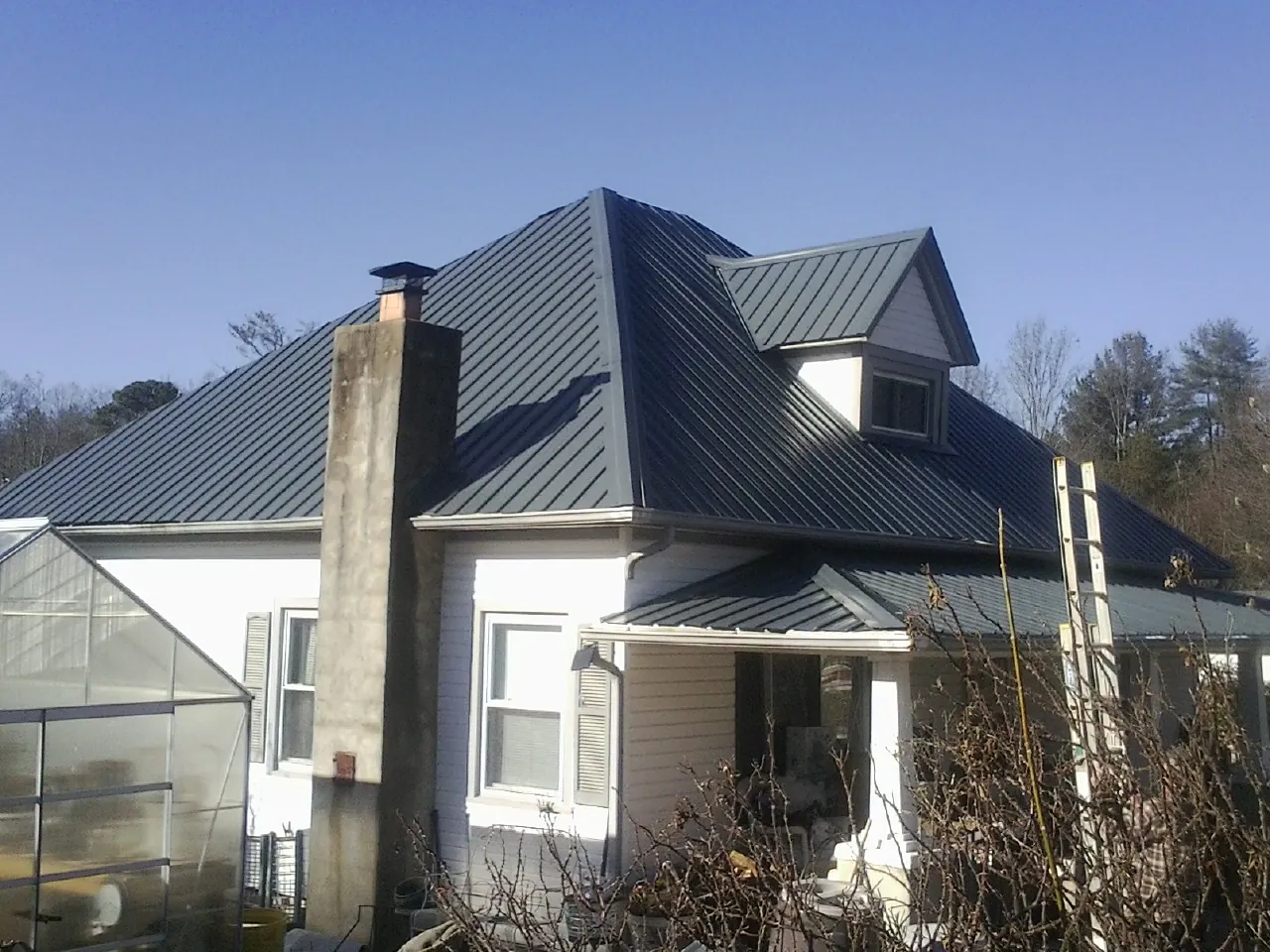 Dark blue standing seam metal roof on a white farmhouse with dormer — Slate & Tile Roof Repair by Roofing Brothers in Royersford