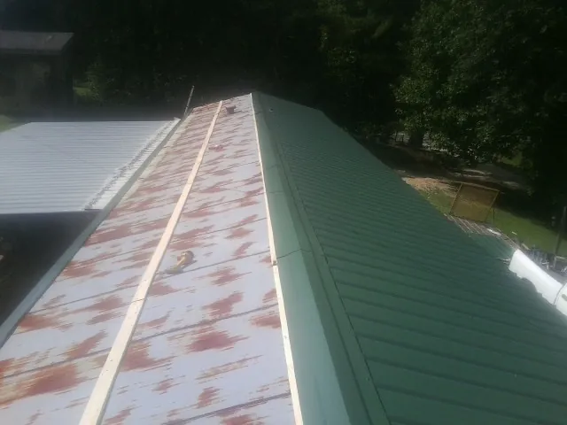 Old rusted panels beside newly installed green metal roofing — Wind Damage Roof Repair by Roofing Brothers in Royersford