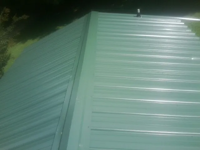 New green metal panels meeting at the ridge of a roof — Flat Roof Repair work by our crew in Royersford