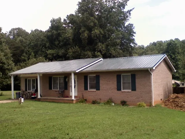 Gray metal roof on a brick ranch house with a side carport in Royersford