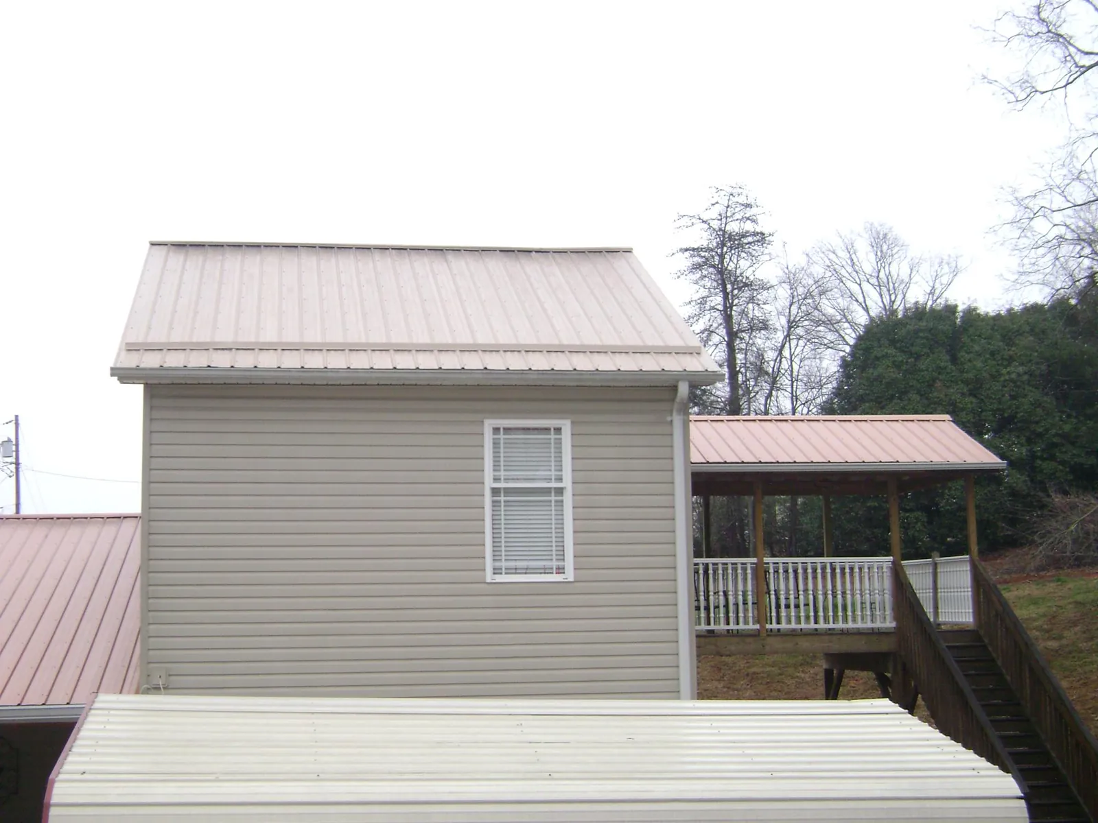 Tan metal roofs on a two story addition and attached porch, from a Roof Replacement job in Royersford