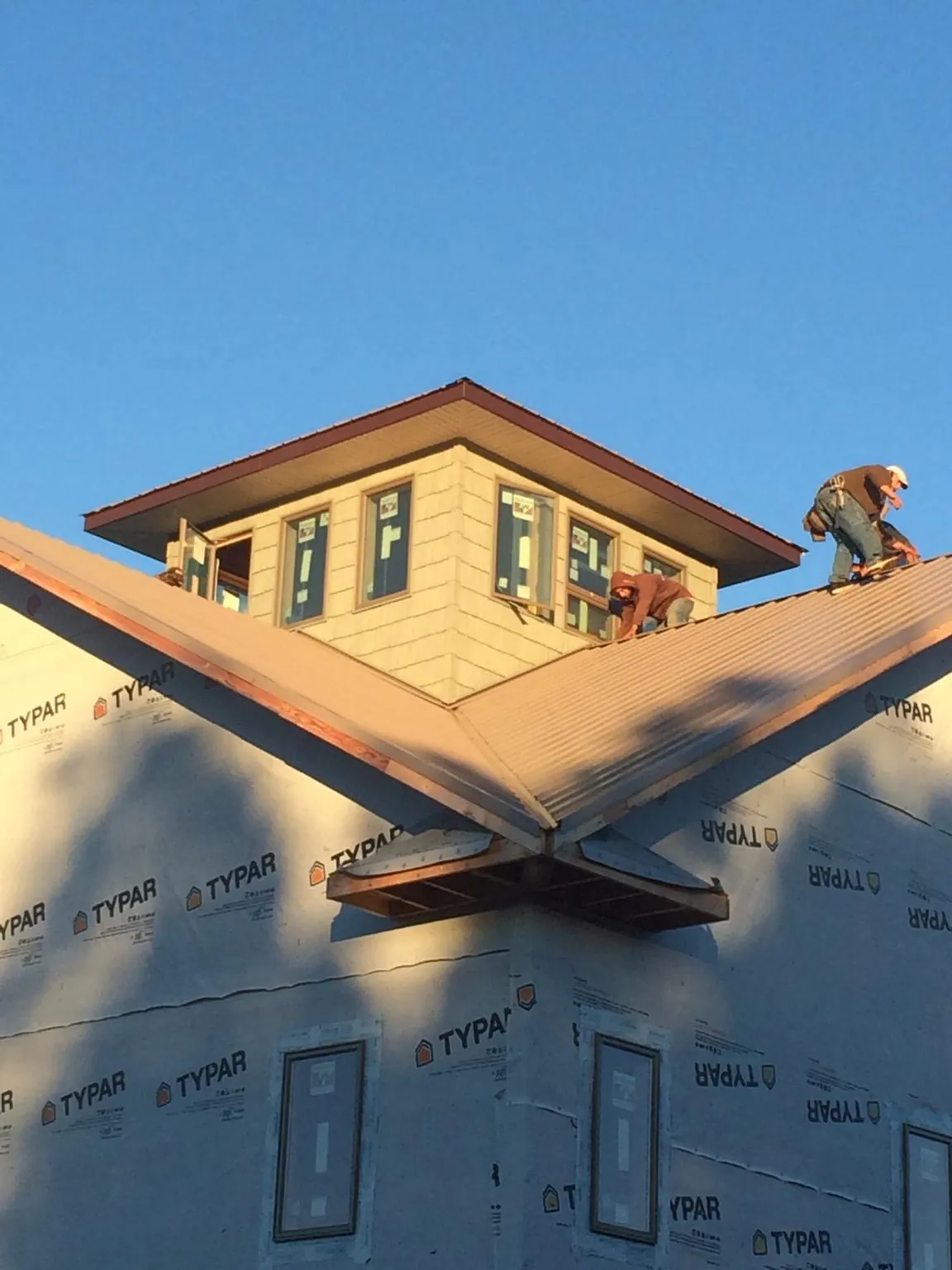 Roofers working around a rooftop cupola on a new metal roof at sunset — Roof Waterproofing in Royersford by Roofing Brothers